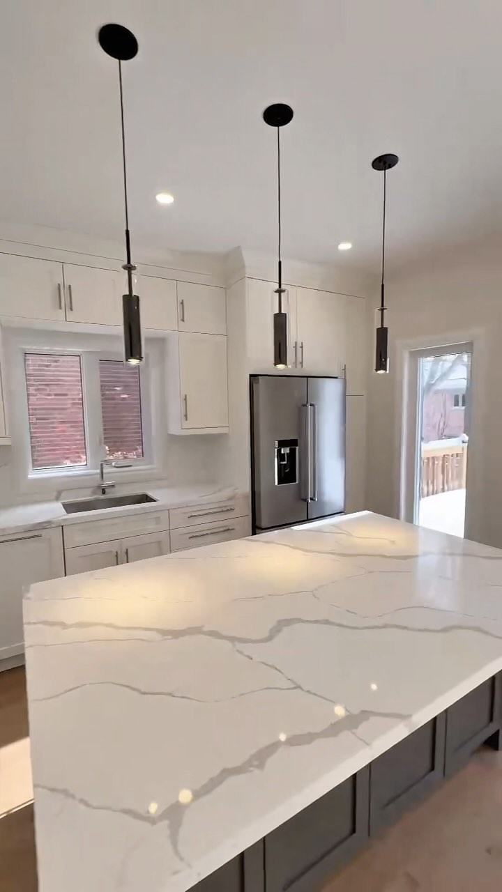 a kitchen with a marble island and a refrigerator