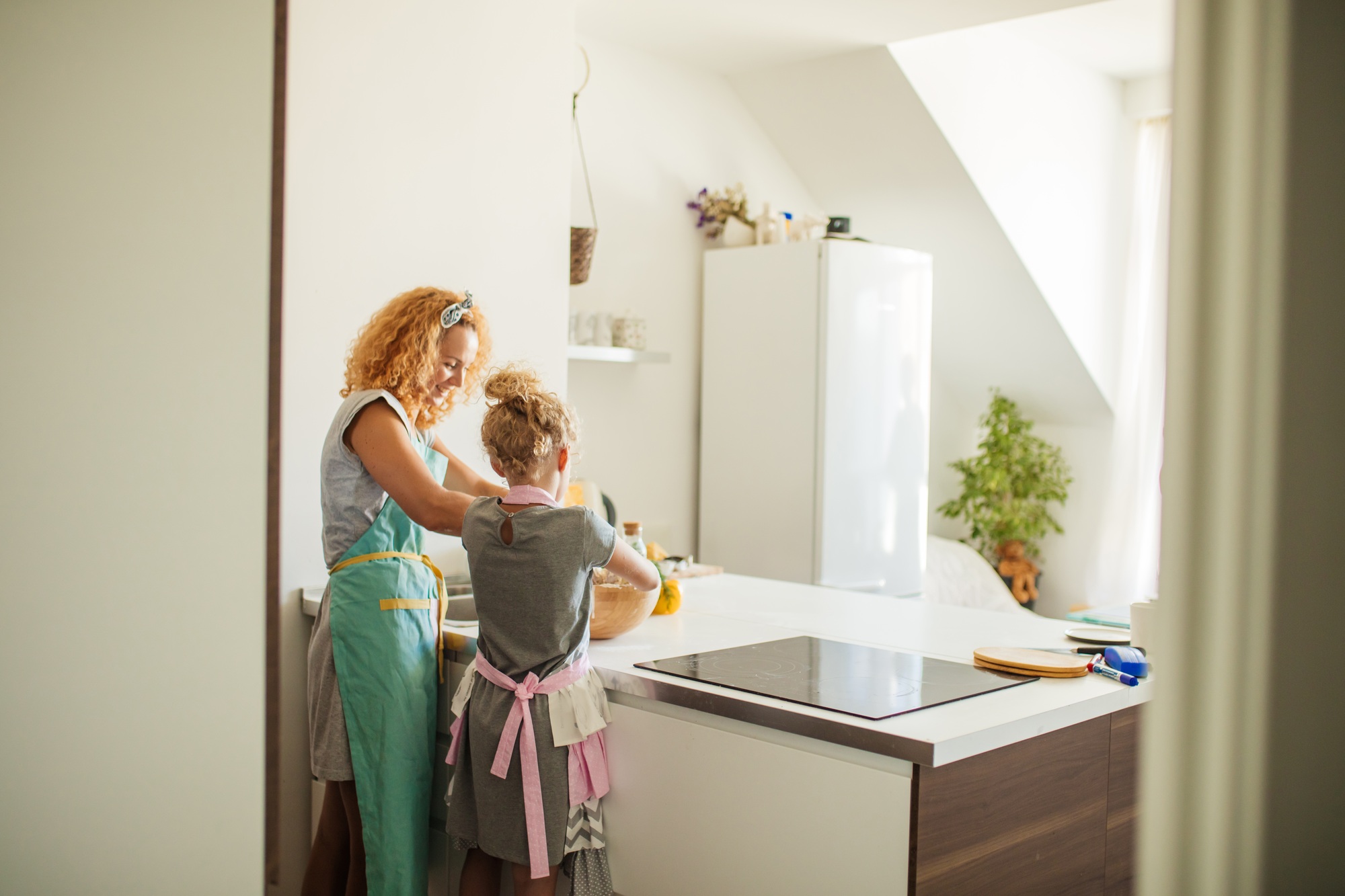 Cooking and home concept - rear view of Mom with daughter kneading dough at home