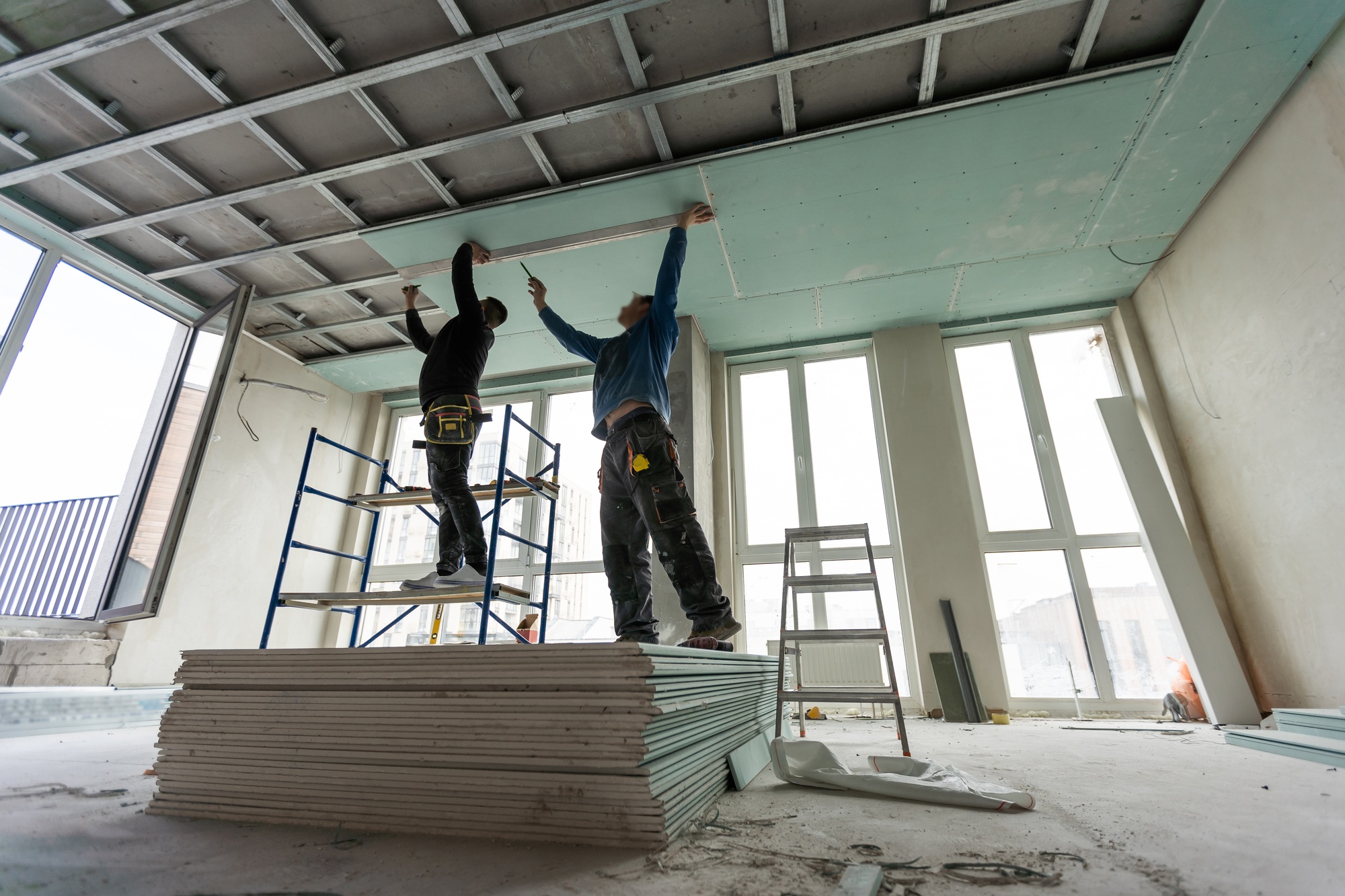 Construction worker assemble a suspended ceiling with drywall and fixing the drywall to the ceiling