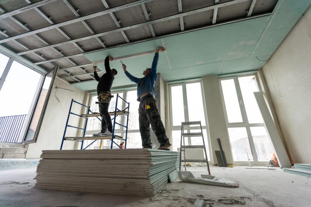 Construction worker assemble a suspended ceiling with drywall and fixing the drywall to the ceiling