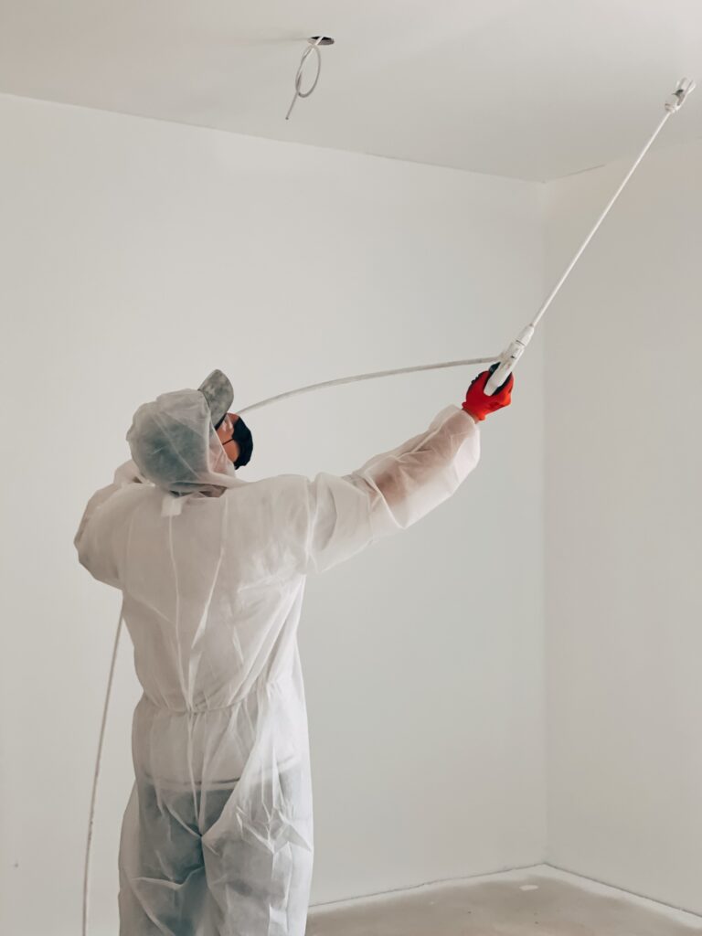 Man paints ceiling with a paint sprayer