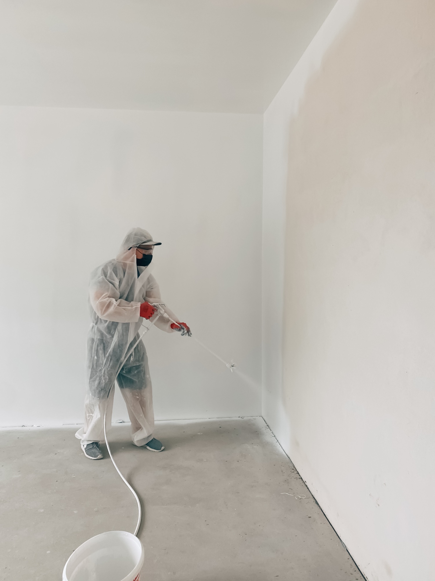 Man paints walls with a paint sprayer