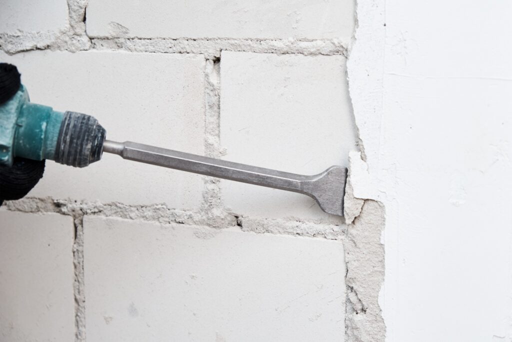 Man with demolition hammer remove stucco from wall. Renovation concept