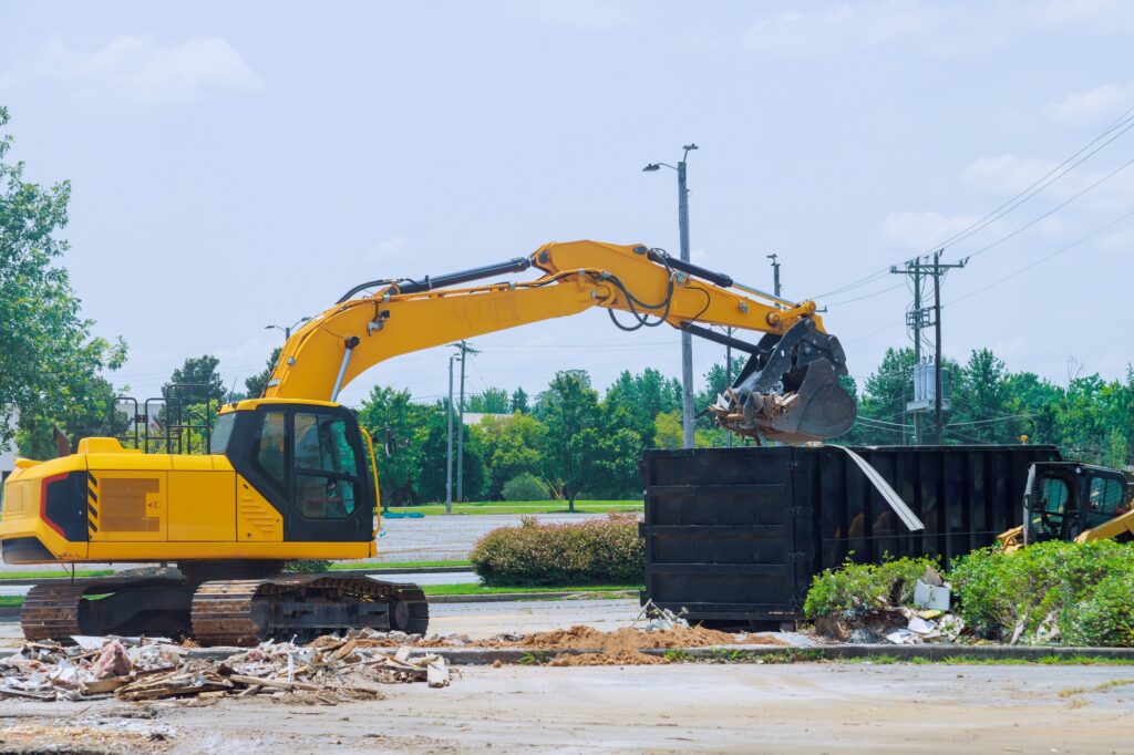 On construction site, an excavator loads construction concrete waste into a disposal container