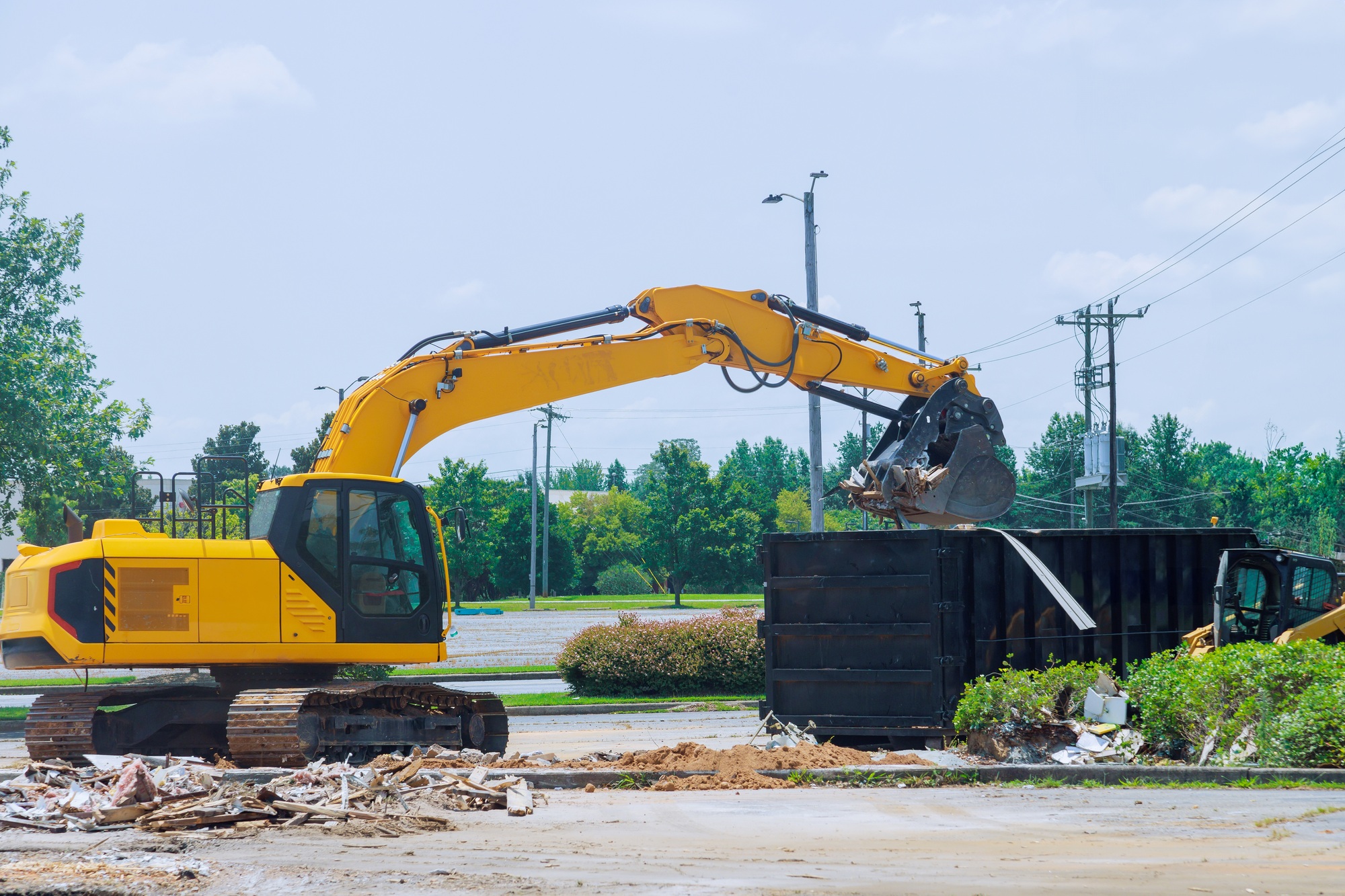 On construction site, an excavator loads construction concrete waste into a disposal container