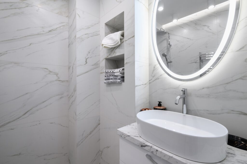 White bathroom interior with marble tiles on the walls